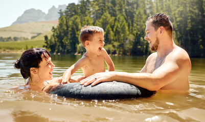 Canvas Print - Family, child floating in tube with parents and swimming in lake with happiness in nature on summer vacation. Energy, adventure and fun outdoor, people in water with laughter, travel and holiday