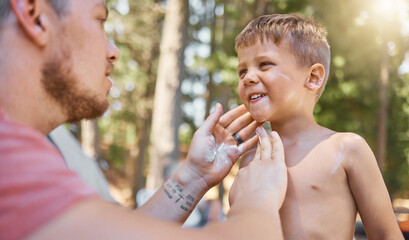father apply sunscreen on child face for protection or safety while camping in a forest or woods for