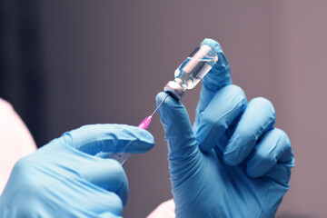 Nurse hand in medical blue glove holding syringe covid-19 coronavirus vaccine liquid from bottle preparing injection coronavirus influenza vaccine vaccination concept.