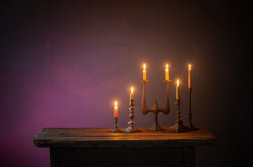 Wall Mural - burning candles in vintage candlesticks on dark background