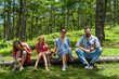 © Tatiana - Family members father, mother and two daughters sit on fallen tree n the forest