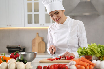 Professional chef cutting fresh tomatoes at white table in kitchen