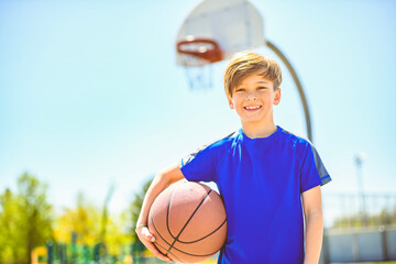 Wall Mural - portrait of a kid boy playing with a basketball in park