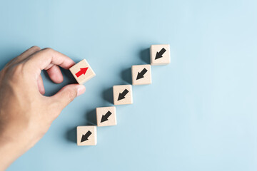 Fototapete - Hand holding wood block with Red arrow and different direction facing opposite direction with black arrow for business disruption and technology transformation and different thinking idea concept.