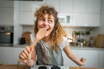 Wall Mural - One happy young adult caucasian woman wear apron in the kitchen smile