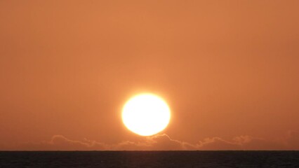 Wall Mural - Sunset time lapse on hot clear sky with low clouds over ocean horizon, night to day transition.