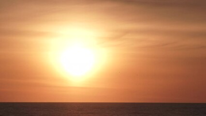 Wall Mural - Bright sun shines on clear sky and drops below water horizon, day to night time lapse.
