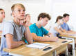 © JackF - Portrait of focused teenage student writing lectures in workbooks in classroom during lesson..