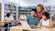 © JackF - Three schoolchildren preparing for lessons in the school library are looking for information on a laptop and taking abstracts in a copybook