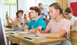 © JackF - Teenager students sitting in class room with smartphones and photographing something.