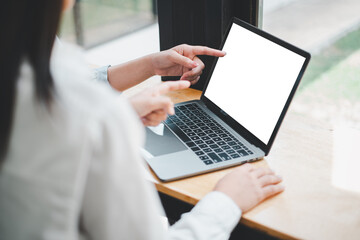 close-up back view of two business woman working on blank screen laptop computer, looking at the scr