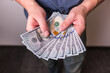 © ShutterFalcon - Man giving money to someone and holding dollar bills