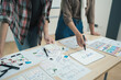 © PaeGAG - Asian team ux developer and ui designer brainstorming about mobile app interface wireframe design on table with customer brief and color code at modern office.
