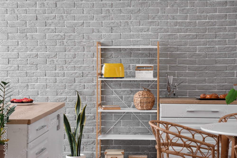 Shelving unit with modern toaster and white counters in interior of kitchen