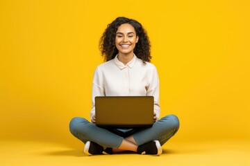 Wall Mural - Smiling attractive young woman sitting on the floor with her legs crossed holding a laptop computer