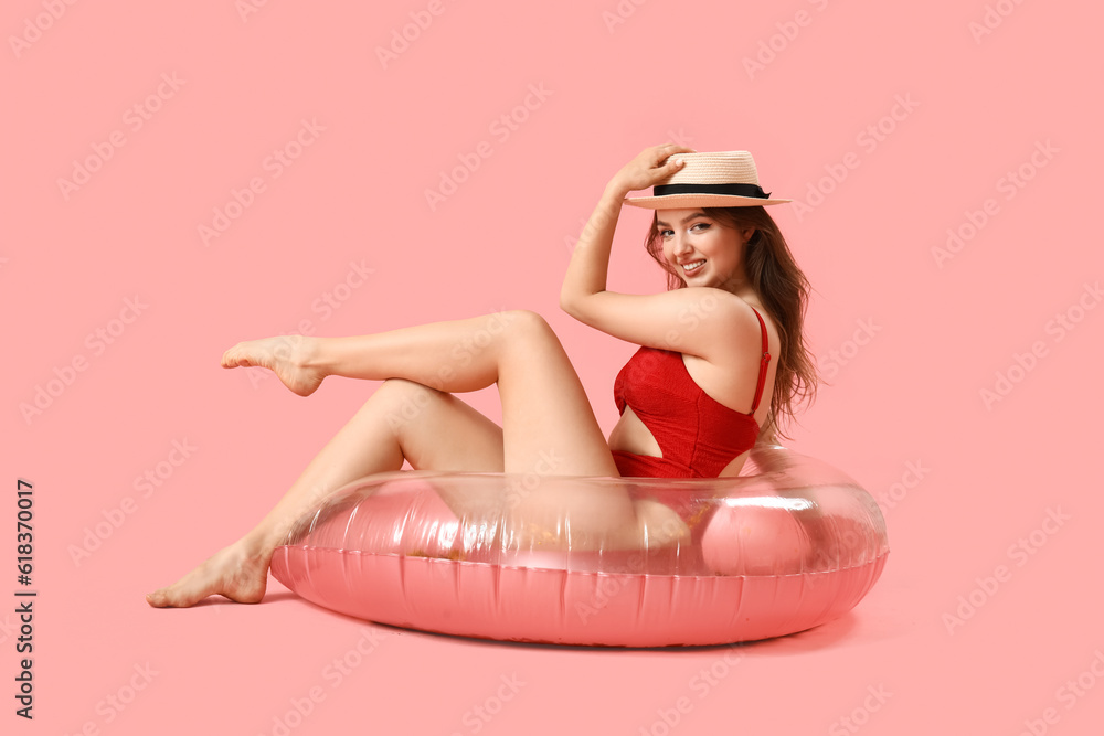 Young woman with swim ring on pink background