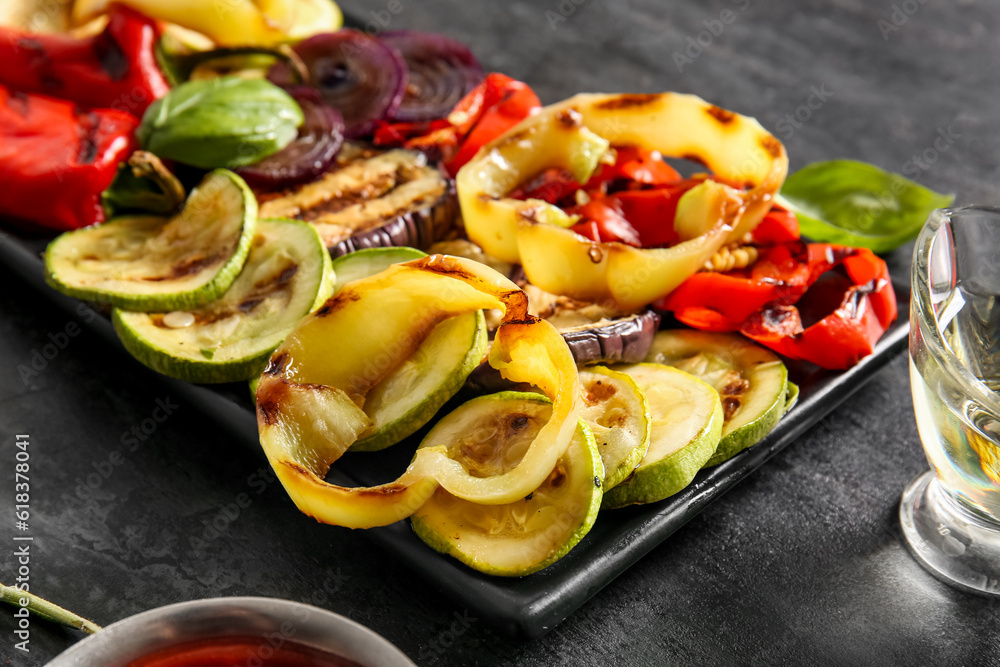 Plate with tasty grilled vegetables on black background