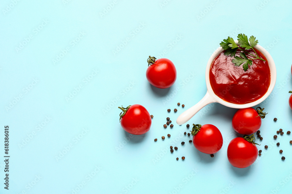 Bowl with tomato paste and fresh vegetables on blue background
