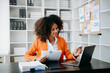 © laddawan - Successful African Businesswoman Analyzing Finance on Tablet and Laptop at modern Office Desk tax, report, accounting, statistics, and analytical research concept..