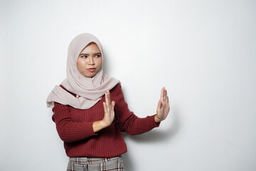 Wall Mural - Serious young Asian Muslim woman making stop gesture and showing rejection isolated over white background