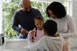 © WavebreakMediaMicro - Happy biracial parents, son and daughter brushing teeth together in bathroom in the morning