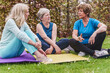 © Lomb - Active senior women friends chatting on yoga mats in sunny spring garden