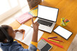© wavebreak3 - African american girl sitting at table using laptop and tablet with copy space for online lesson