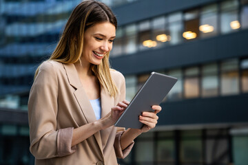 Wall Mural - Successful businesswoman using a digital tablet while standing in front of business building.