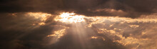 A Breathtaking Sky Panorama Showcasing Rays Of Sunlight Piercing Through Gaps In The Ominous Dark Clouds.
