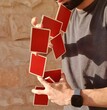 Young man performing a card trick with a deck of red playing cards.