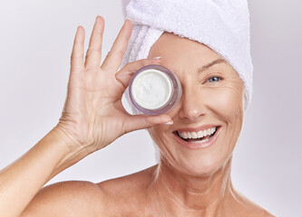 Portrait, cream and beauty with old woman, happy with skincare and dermatology on white background. Sunscreen, moisturizer and face care, female model apply lotion with glass container and skin