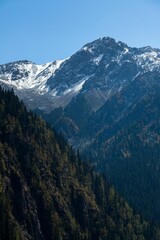 Sticker - Majestic snow-covered mountain peaks against lush green forest in Sichuan Province, China