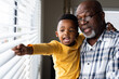 © Wavebreak Media - Happy african american grandfather and grandson embracing and looking through window