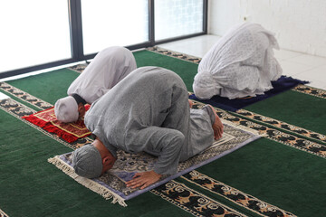 Asian muslim family praying jamaah together and doing sujud movement or called a Sajdah or prostration, top view