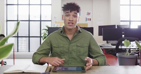 Wall Mural - portrait of biracial male designer in video call at computer in casual office, slow motion