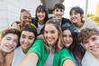 © julio - Multi-ethnic group of nine teenagers taking a selfie sitting on steps