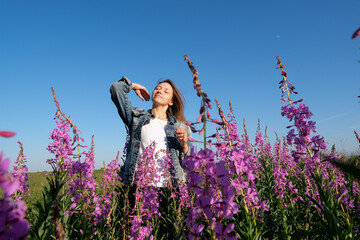 smiling young woman with hat on willow-herb flowers field. happiness, nature, summer, vacation concept