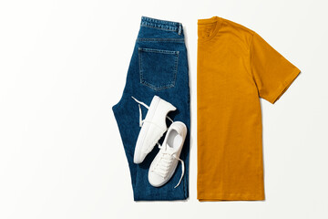 Wall Mural - Orange t-shirt, blue jeans and white sneakers on white background