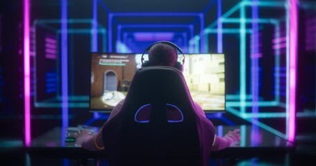 Wall Mural - Back View Footage of a Professional Young Woman Playing First-Person Shooter Online Video Game on a Computer. Streaming and Gaming Concept. Room Lit by Neon Lights in Retro Arcade Style