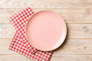 Wall Mural - Top view on colored background empty round pink plate on tablecloth for food. Empty dish on napkin with space for your design