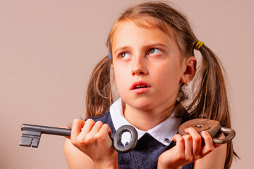 Portrait off confused young girl holding big key and small lock as symbo of bad password, security and password management.