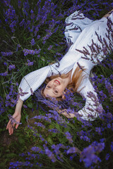 Canvas Print - A smiling woman dressed in a white dress lies in the middle of a lavender field, surrounded by lavender wreaths as she smiles