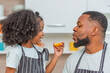 © BESTIMAGE - african afro hair black kid Cute taste oranges citrus sour flavour on lips mouth with daddy in kitchen. back african daughter kid afro hair and daddy frowning face for taste is sour of sliced orange