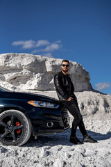 Wall Mural - Handsome man with car standing. Young transport driver outdoor looking.