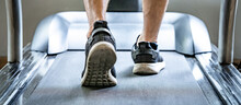 Close Up Of Male Feet In Sneakers Or Sport Footwear Running On Treadmill In Fitness Gym. Indoor Cardio Workout Machine