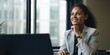 © meredith blaché  - Smiling happy middle-aged BIPOC businesswoman executive CEO in a business suit using a computer to work with a client in an office setting -room for copy text, generative AI