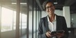 © meredith blaché  - Smiling happy middle-aged BIPOC businesswoman executive CEO in a business suit using a computer to work with a client in an office setting -room for copy text, generative AI