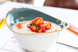 Delicious breakfast for children: sweet milk semolina porridge with strawberries on a beautiful plate, strawberries on a gray background. Semolina porridge with milk for lunch
