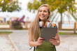© luismolinero - Young blonde woman at outdoors holding a tablet