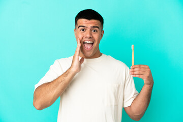 Wall Mural - Young handsome man brushing teeth over isolated blue background with surprise and shocked facial expression